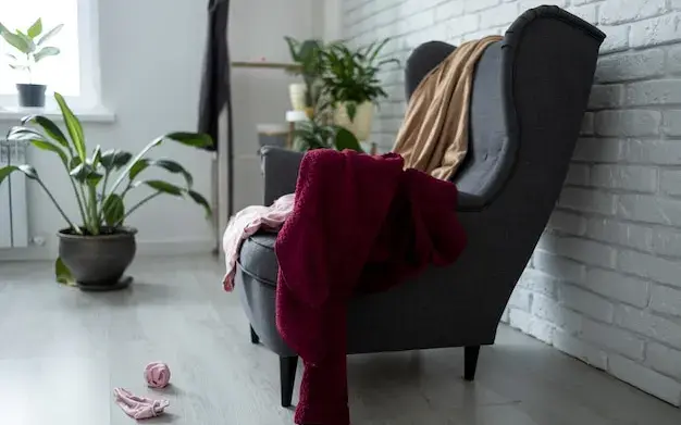 Poltrona com roupas e mantas acumuladas no assento